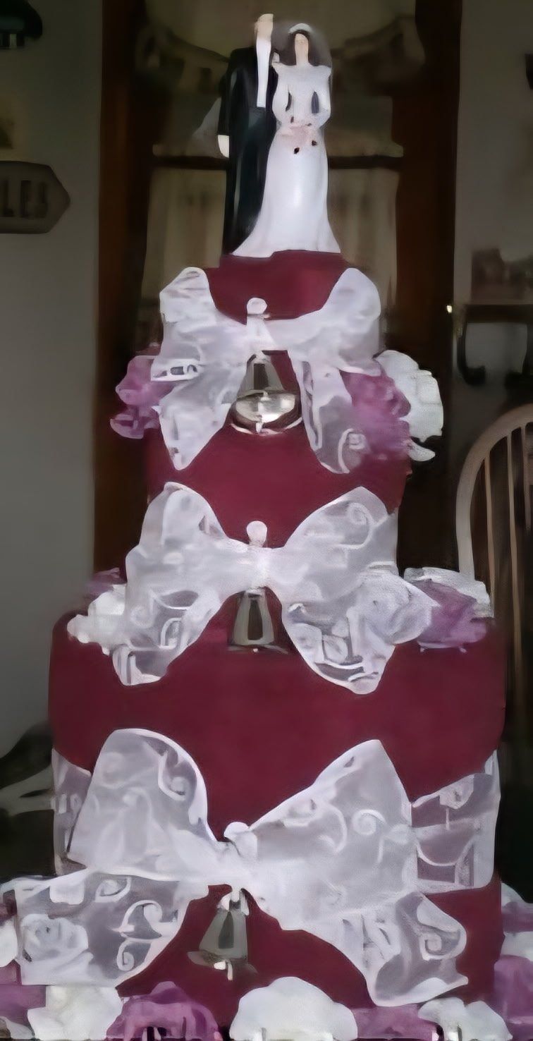 Red and white wedding towel cake topped with a bride and groom
