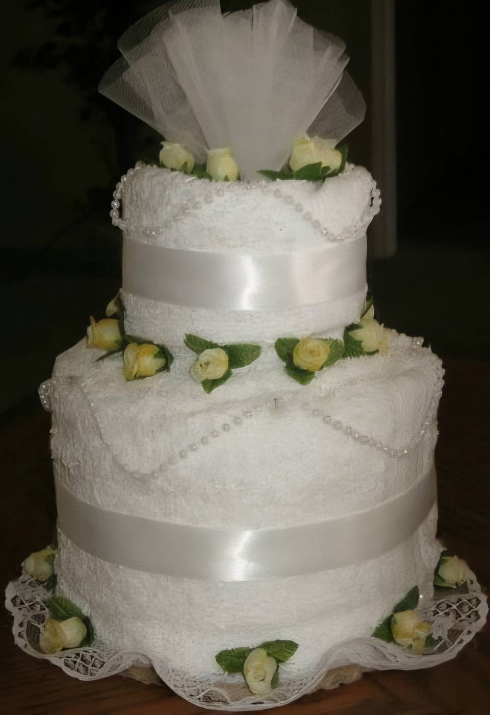 White towel cake with yellow rosebuds and tulle topper